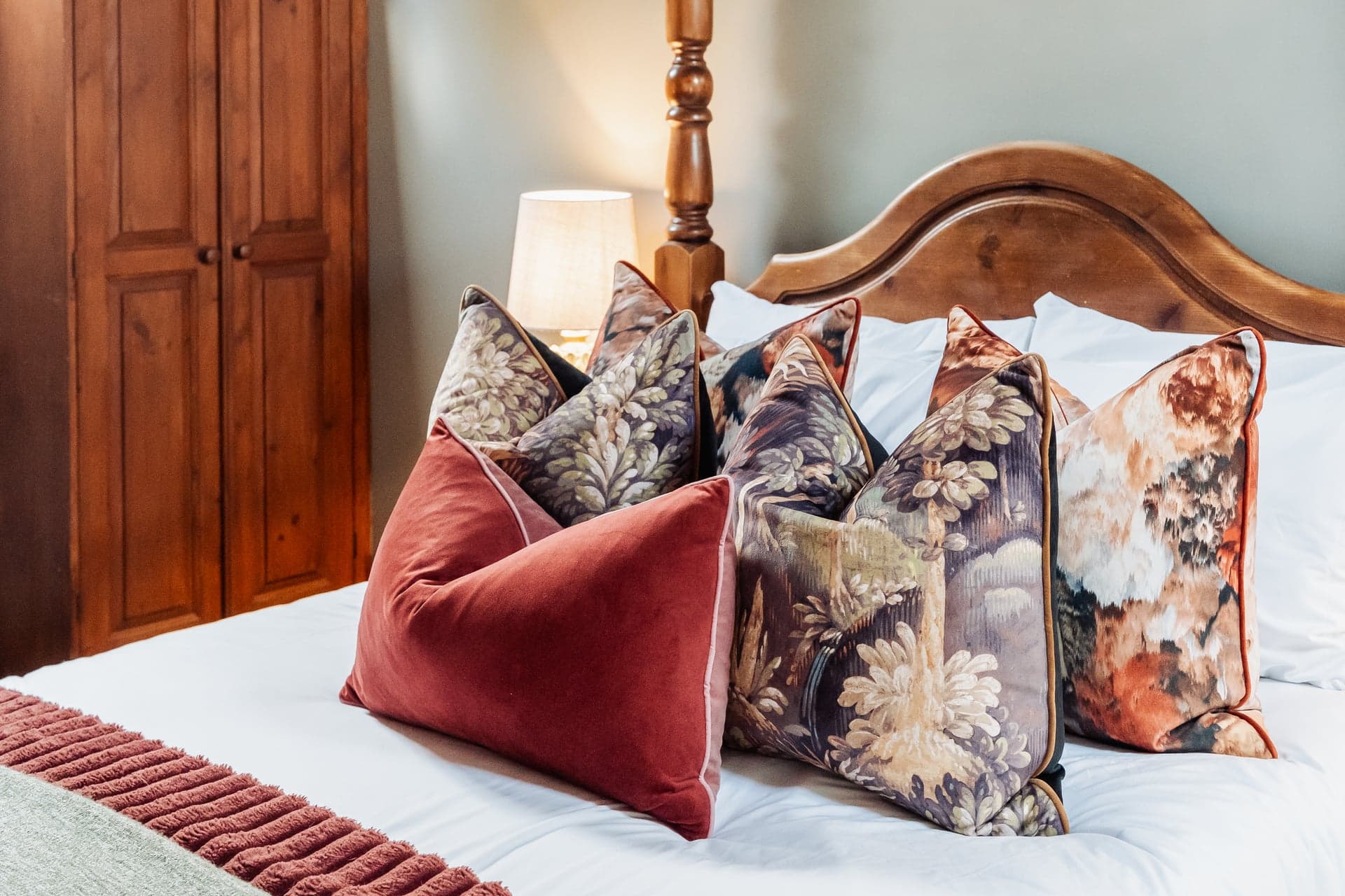 Detail of a boutique room at The Bull on the Green, Newick — patterned cushions on a four-poster bed